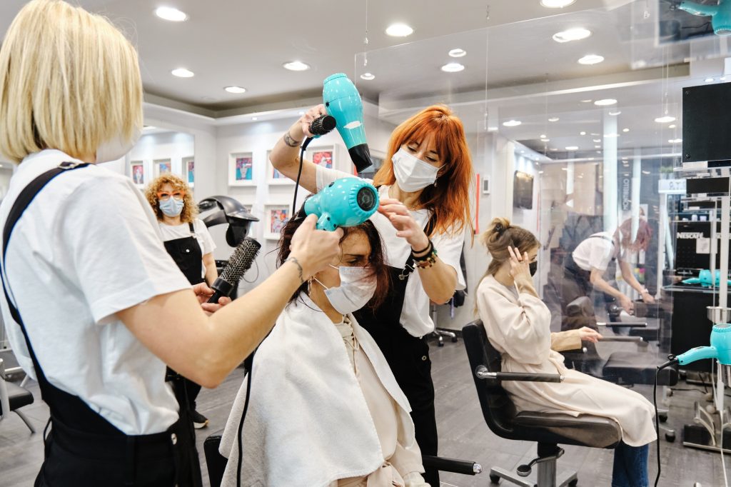 two hairdressers drying the hair of a client at the hair salon